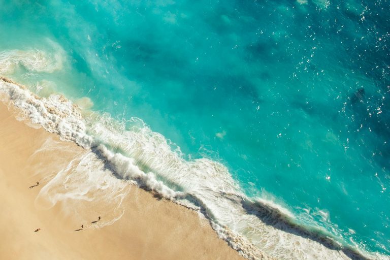 Stunning aerial view of a serene beach in Bali with turquoise waters and soft sands.